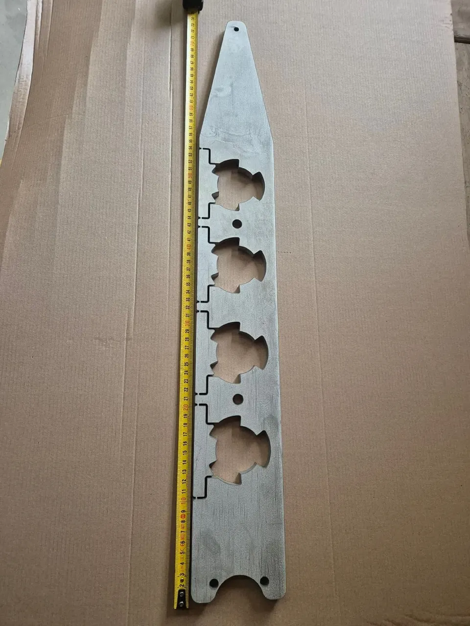 Metalplade med målebånd placeret på pap.